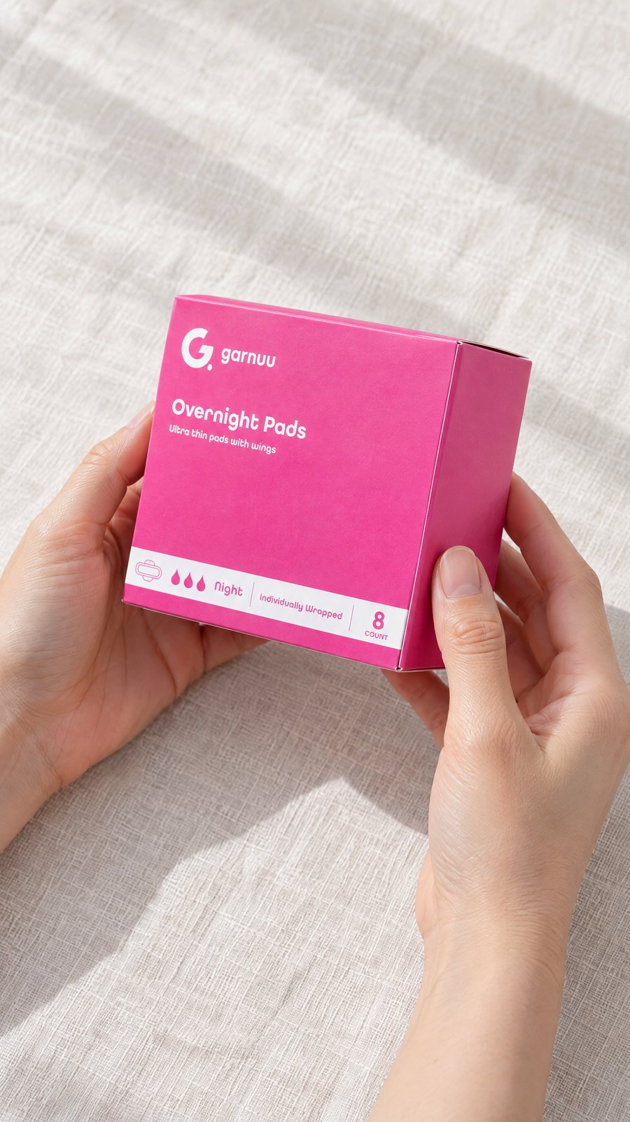 Two hands turning a Garnuu Overnight Pads box over to read its side panel